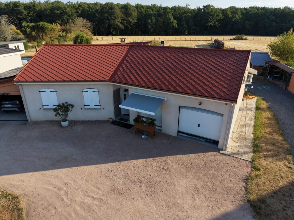 Vue aérienne d’une maison avec garage et toiture rouge