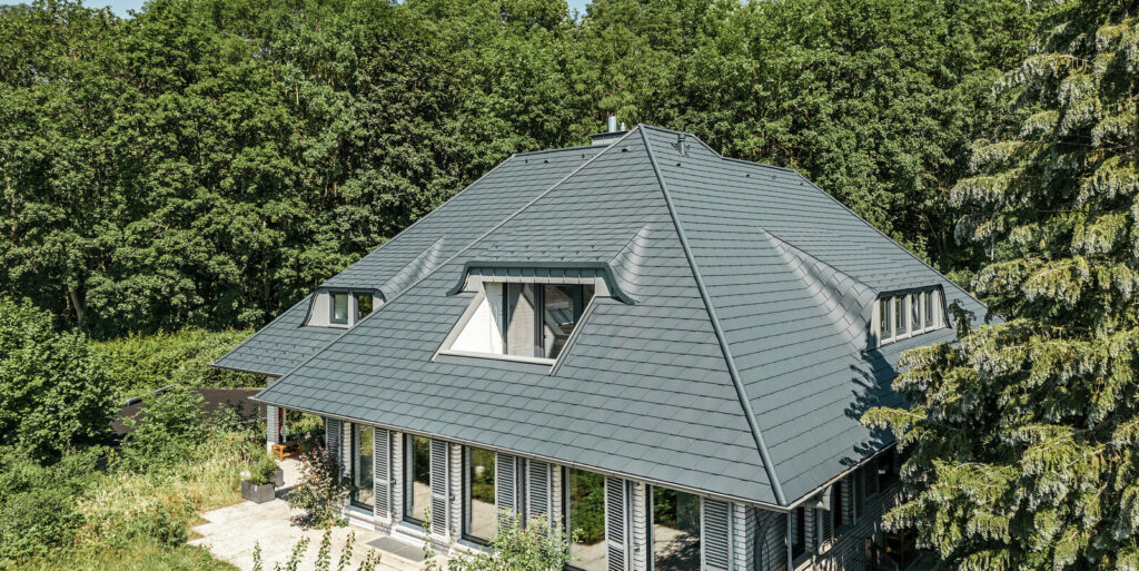 Maison entourée d’arbres avec toiture grise à plusieurs pans